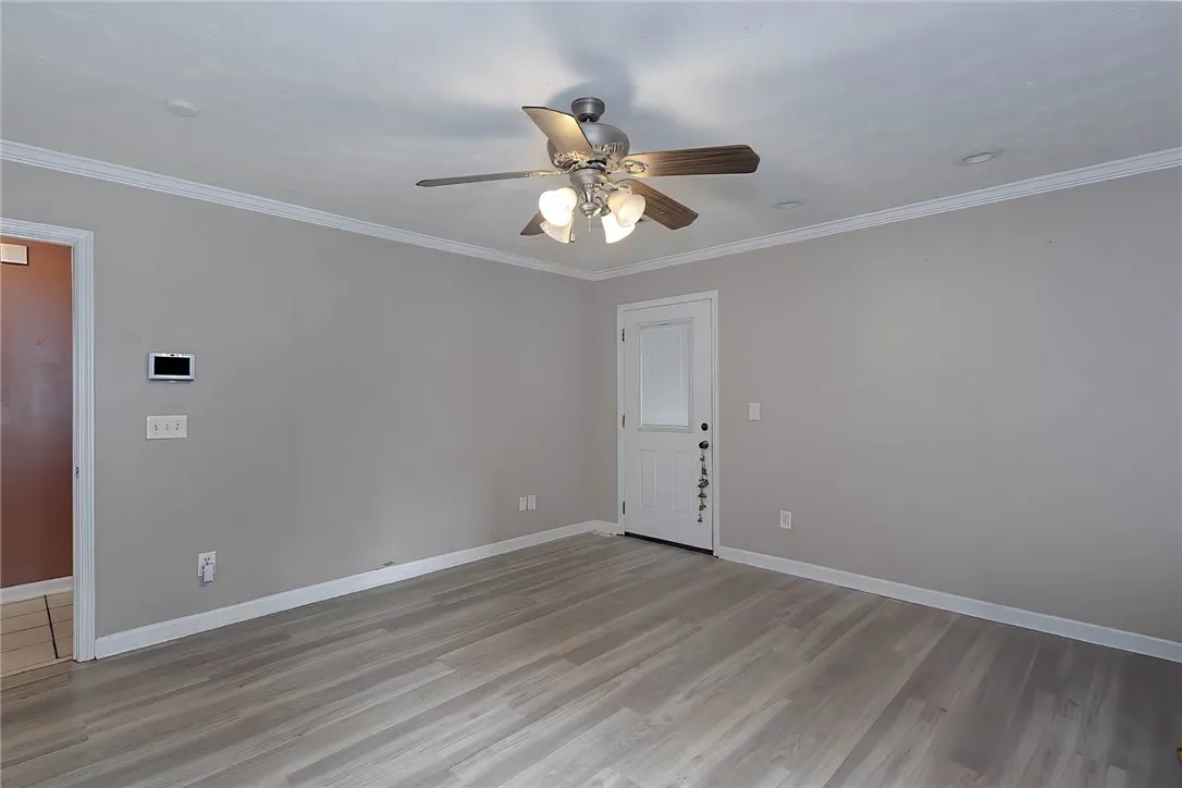 A versatile living area with light wood flooring and ceiling fan offers comfort.