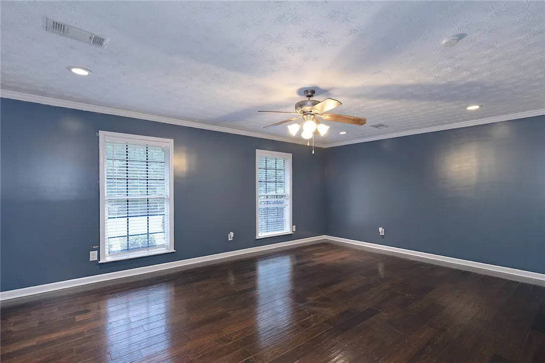 Rich hardwood flooring complements the deep wall tones in this inviting bedroom.