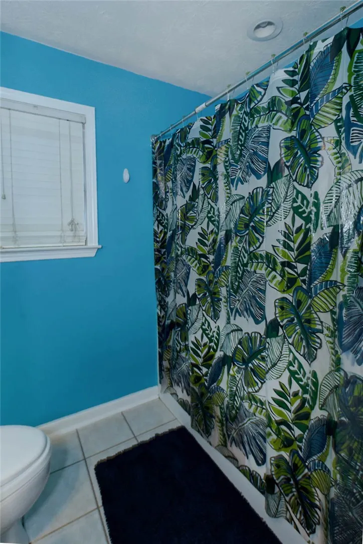 A vibrant bathroom features clean tile flooring and a decorative shower curtain.