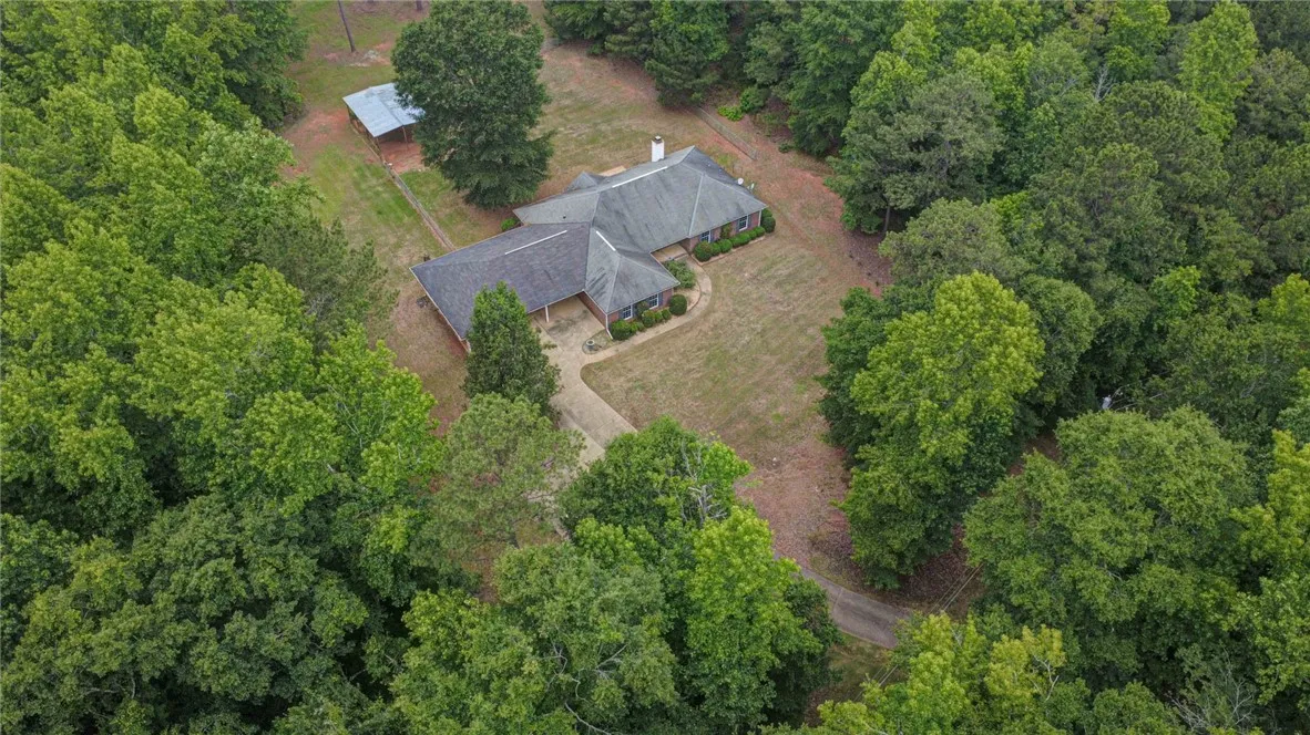 Discover a private woodland estate, featuring a charming residence nestled amidst a vibrant canopy of mature trees.