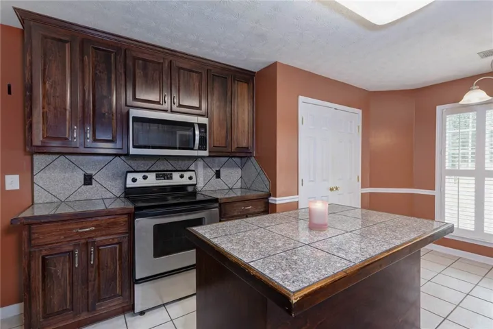 A well-appointed kitchen features dark wood cabinetry and a tiled island, illuminated by natural light.