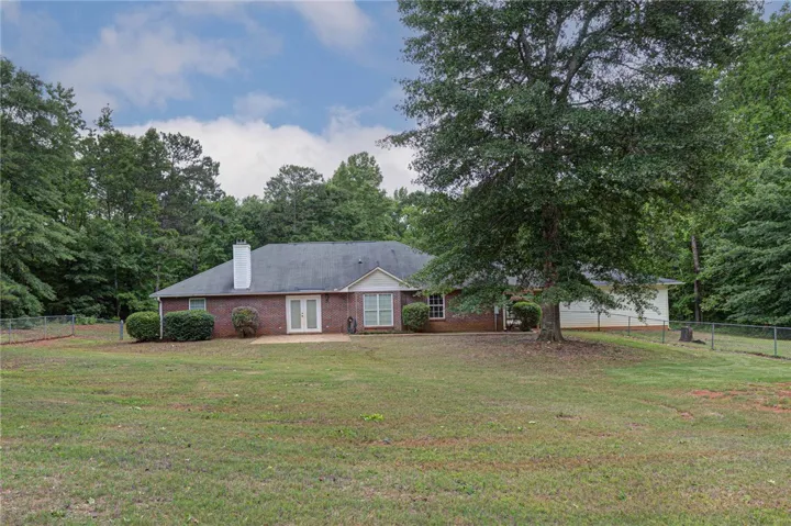 A spacious backyard with mature trees and a fenced perimeter offers a serene outdoor escape.
