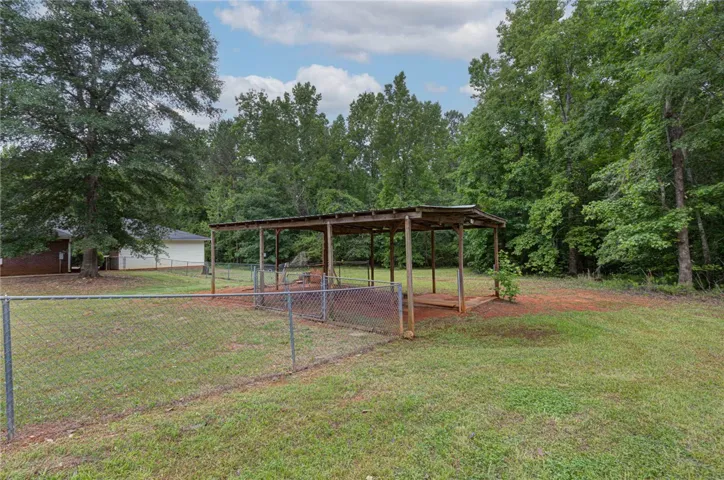 A spacious backyard with mature trees and a sturdy, covered shelter.