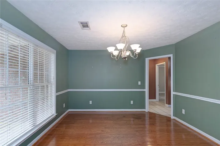 A refined dining space features gleaming hardwood floors and a classic chandelier, poised for elegant gatherings.