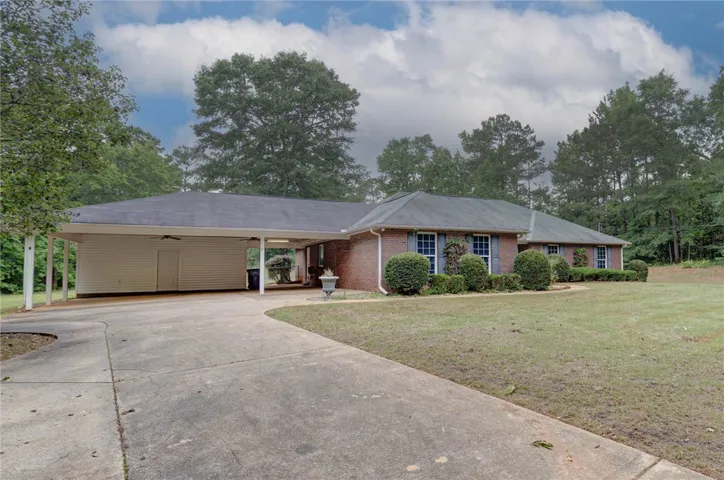 A well-maintained ranch-style home featuring a convenient attached carport and mature landscaping.