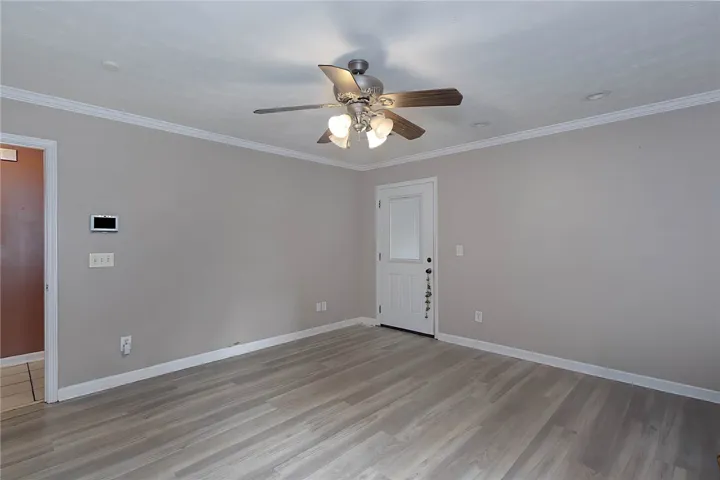 A versatile living area with light wood flooring and ceiling fan offers comfort.
