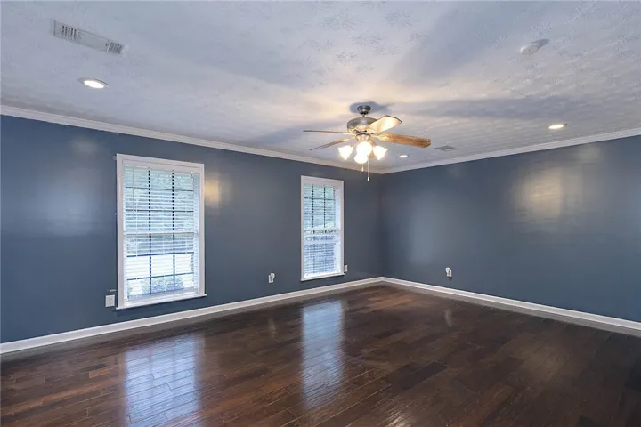Rich hardwood flooring complements the deep wall tones in this inviting bedroom.