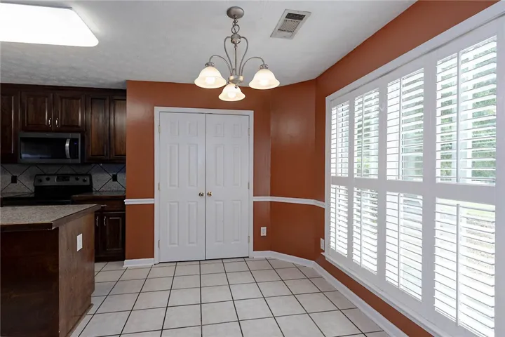 A well-lit kitchen area features rich cabinetry and crisp white plantation shutters.