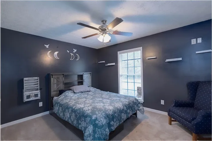 A comforting bedroom space features plush carpeting and an overhead ceiling fan for optimal comfort.