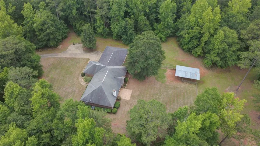Discover a private retreat nestled among verdant trees with ample space and a functional outbuilding.