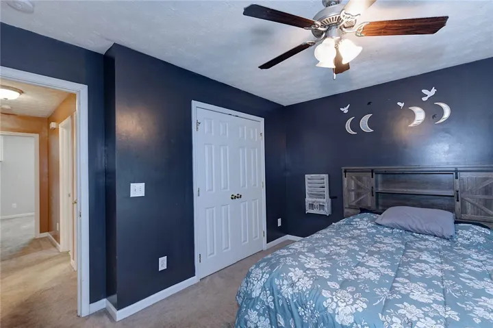 A well-lit bedroom features plush carpeting and a convenient ceiling fan.