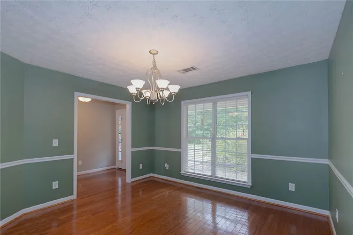 Hardwood floors and a grand chandelier define this welcoming dining space.