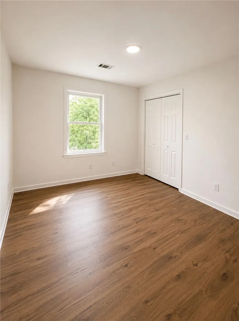 A quiet bedroom showcases durable wood flooring and ample natural light from a double window.
