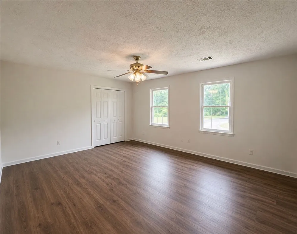 A versatile space features rich wood flooring, double windows, and a functional closet.