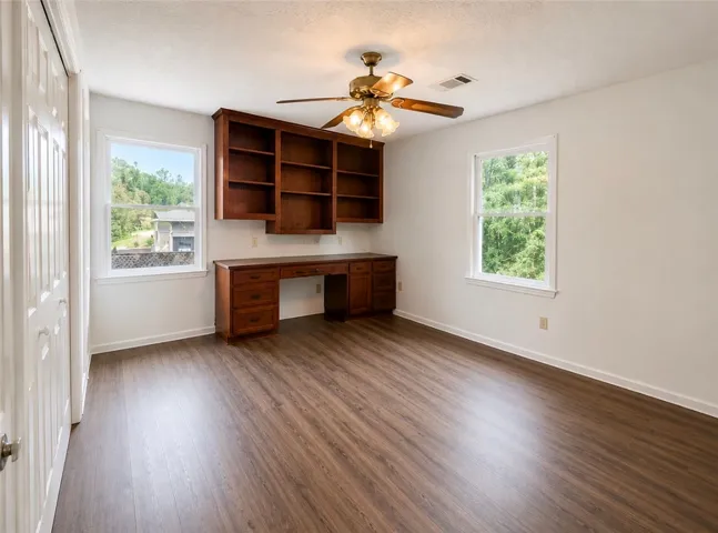 A versatile space features rich wood built-in shelving and desk, complemented by natural-toned flooring.