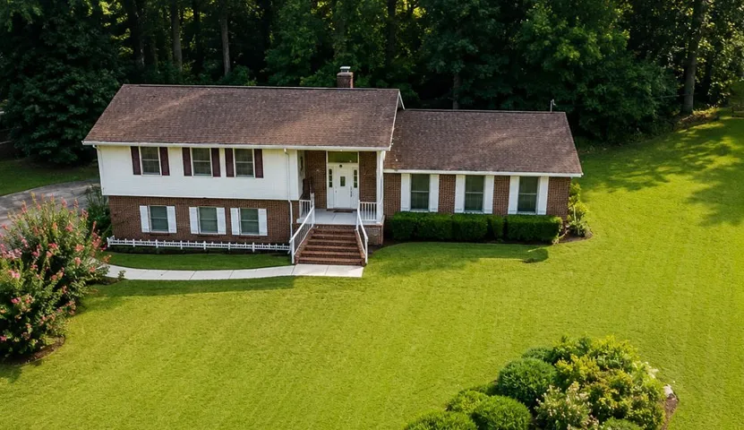 Well-maintained brick and siding residence, set against a backdrop of mature trees, offering a gracious welcome.