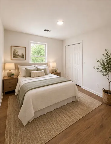 A quiet bedroom retreat with wood flooring and a large window inviting natural light.