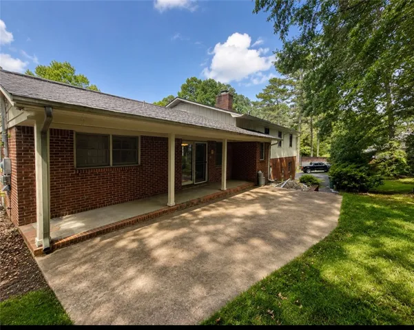 A spacious rear patio offers abundant outdoor entertaining space, nestled beside mature trees.