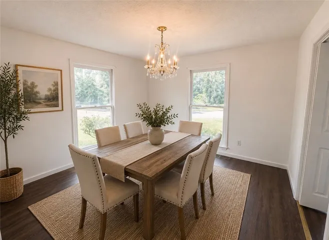 A classic chandelier illuminates this elegant dining area, framed by two large windows that invite the outside in.