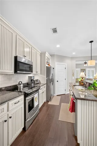 A well-appointed kitchen features dark granite countertops, stainless steel appliances, and rich hardwood flooring.