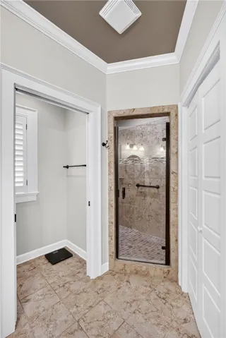 A well-appointed bathroom features crown molding, tile flooring, and a glass-enclosed shower.