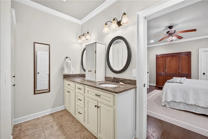 Dual vanities with granite counters provide ample space in this well-appointed bathroom, adjoining a tranquil bedroom.