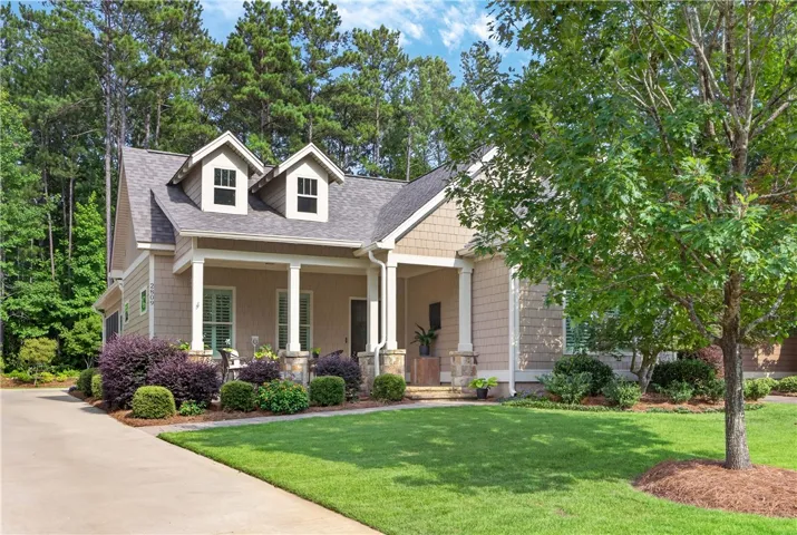 A welcoming façade boasts a covered front porch, dormer windows, and a manicured lawn.