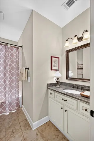 A well-appointed bathroom features a single vanity with granite counters and tiled flooring.