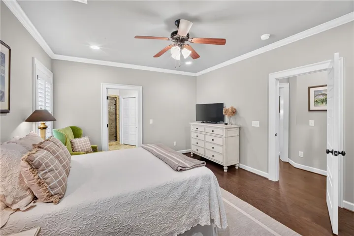 Hardwood floors and a ceiling fan create a comfortable atmosphere in this well-appointed sleeping area.