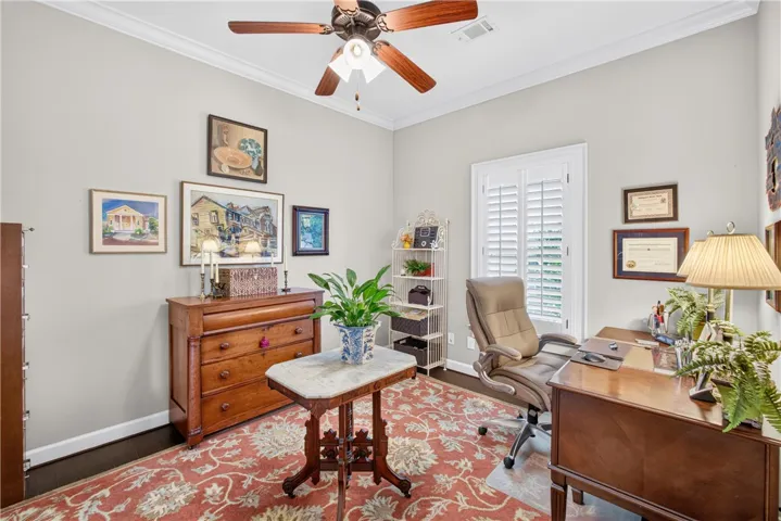 A refined home office with crown molding and dark hardwood flooring, perfect for productive endeavors.
