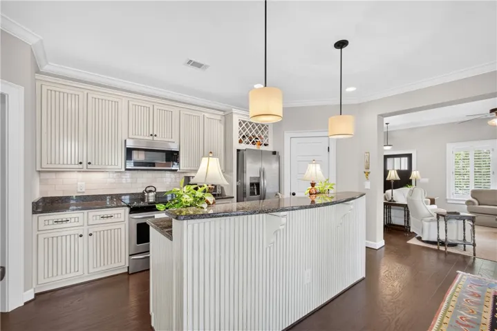 Granite counters and stainless appliances complement this kitchen's rich hardwood flooring.