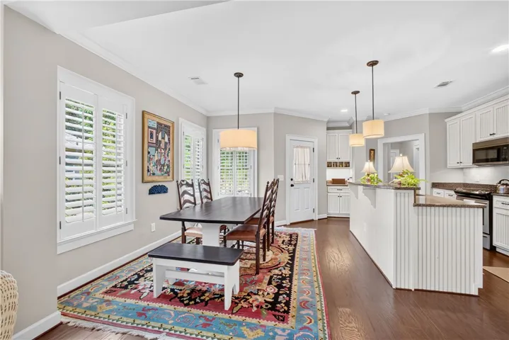 Hardwood floors flow through this luminous dining area, seamlessly connecting to a modern kitchen with a breakfast bar.