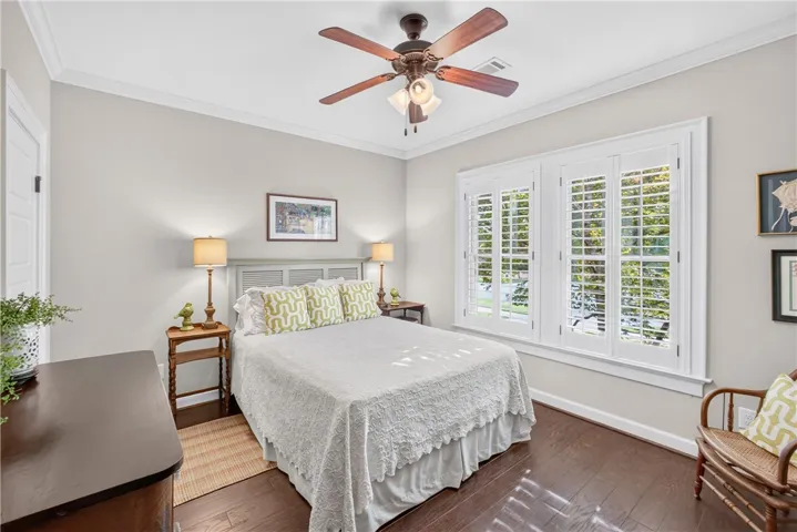 Well-lit sleeping quarters with rich hardwood floors and window shutters creating an inviting atmosphere.