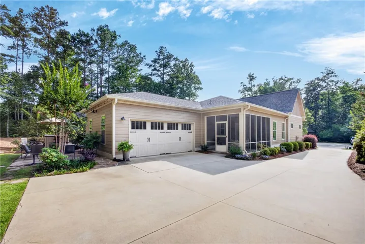A well-maintained concrete driveway leads to a charming residence featuring a garage and a delightful screened porch.