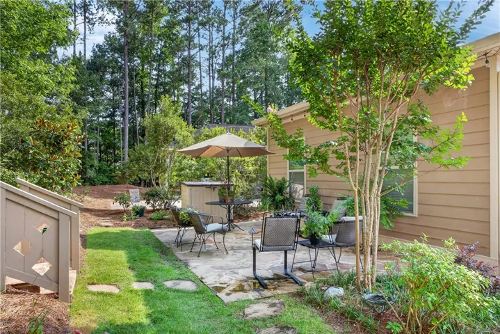 Enjoy outdoor entertaining on a private stone patio, embraced by mature trees and verdant landscaping.