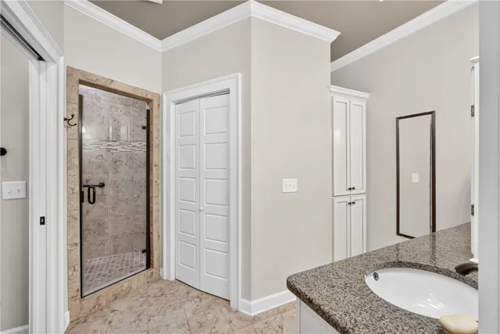 Luxurious tile flooring and shower surround enhance this well-appointed bathroom with granite counters.