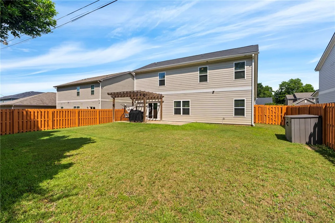 A generous backyard, fully fenced, features a pergola-covered patio, ideal for outdoor gatherings.