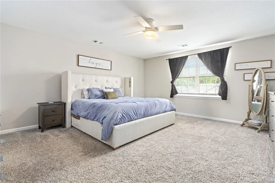 A restful primary bedroom provides abundant comfort and soft, textured carpet underfoot.