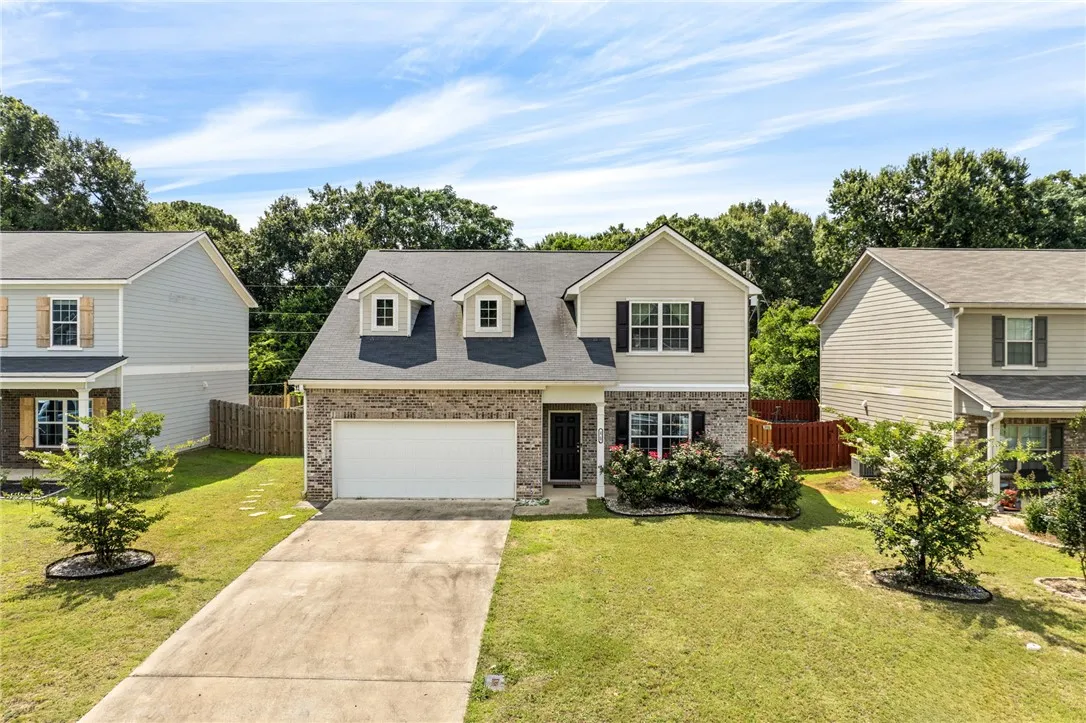 A classic brick and siding residence with a welcoming lawn and a spacious driveway.