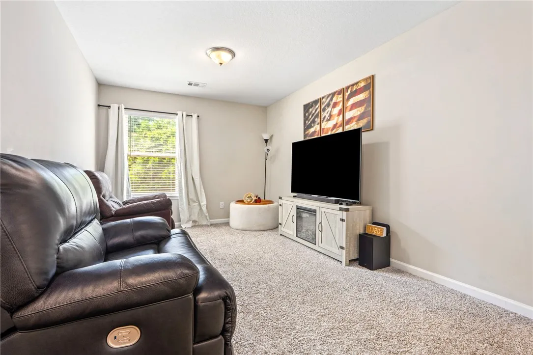 Well-lit room with plush carpet, a large window, and light-toned walls.