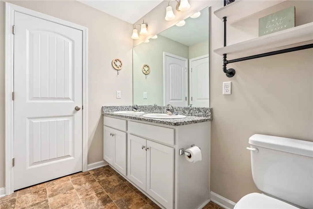 Double vanity with ample counter space and well-lit mirror offers practical elegance.
