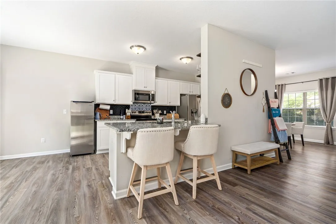 A well-appointed kitchen features a granite island with breakfast bar seating and stainless steel appliances.