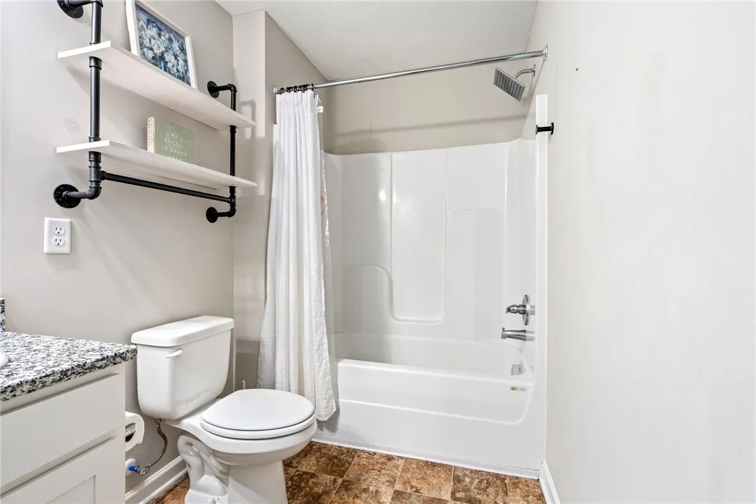 A well-appointed bathroom offers a convenient shower-tub combination and functional open shelving.
