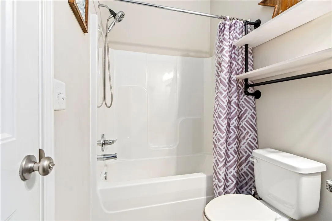 Functional full bathroom featuring a tub-shower combination and convenient shelving.