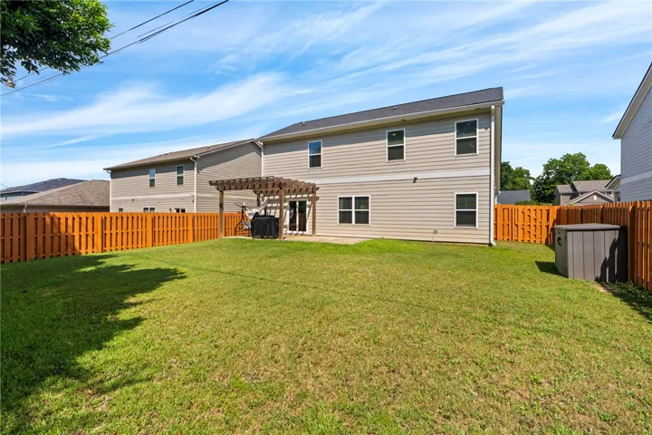 A generous backyard, fully fenced, features a pergola-covered patio, ideal for outdoor gatherings.