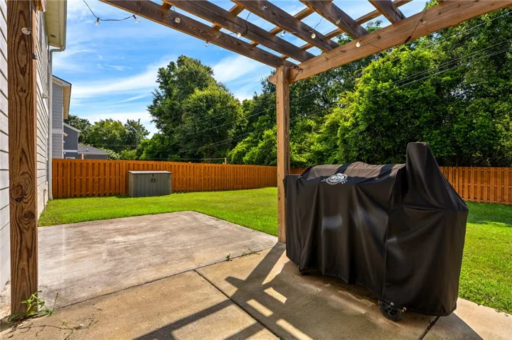 A spacious backyard patio with a wooden pergola offers a perfect spot for outdoor dining and relaxation.
