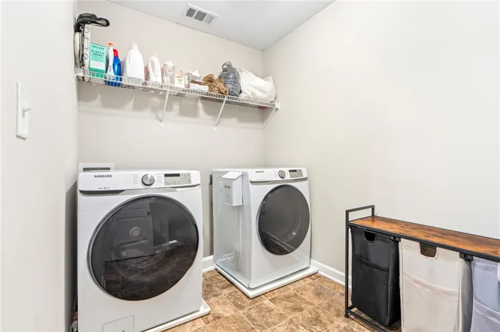 Functional laundry space featuring durable tile flooring and convenient shelving.