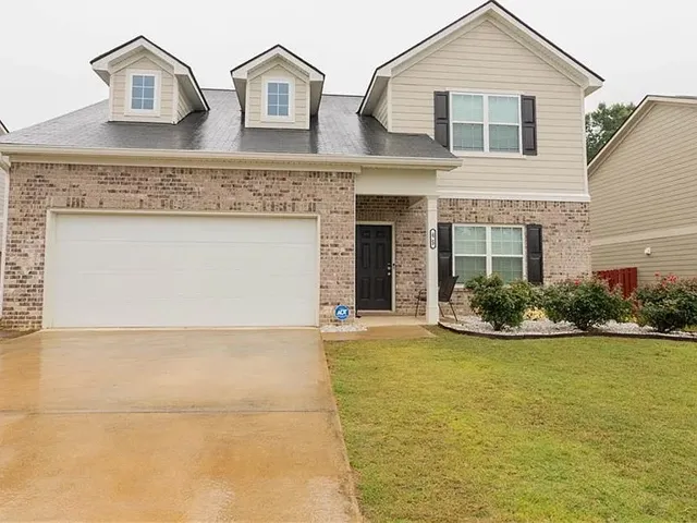 A classic brick and siding home with an inviting front entry and lush landscaping.