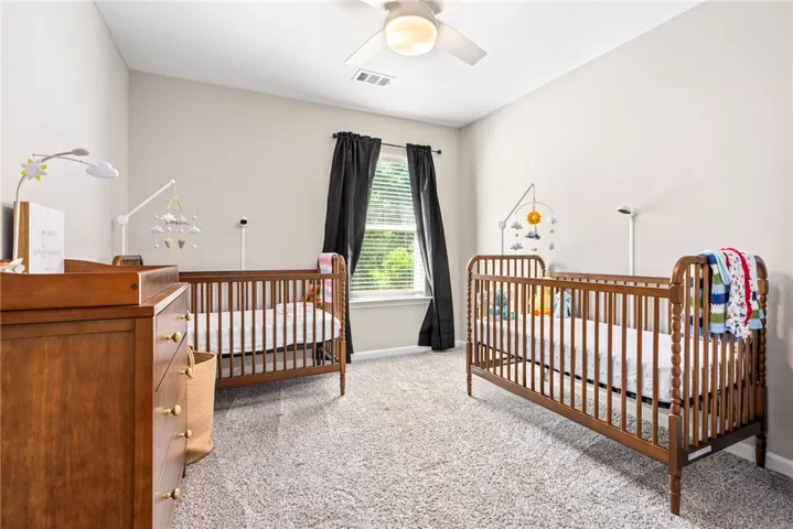 A well-lit bedroom provides ample space for dual cribs, creating a peaceful environment.