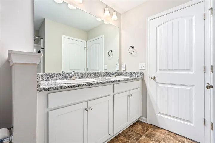 Twin vanities with granite counters provide ample space in this well-appointed bathroom.